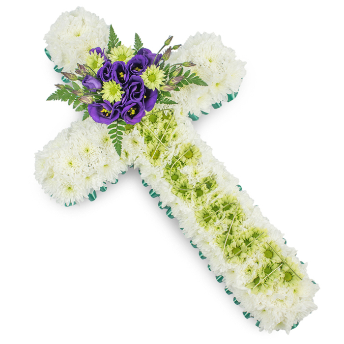 In this photograph, a meticulously crafted floral cross rests against a stark white background, its elegant structure designed as a meaningful sympathy tribute for funerals and memorials around Belvedere. The cross is clearly defined by a narrow border of vivid green ribbon that traces the full outline, neatly framing the arrangement like a gentle embrace. Within this border, the surface is entirely covered with compact, pure white spray chrysanthemums. Their small, rounded petals overlap in countless layers, creating a densely textured field of white that suggests purity, spiritual peace, and a quiet, contemplative mood, fitting for services held near Nuxley Road or local Belvedere churches.
The vertical arm of the cross features a central strip of lime-green button chrysanthemums, running from just below the focal point down toward the base. These fresh green blooms provide a subtle yet distinct contrast against the snowy white background, symbolising renewal and hope. Over this strip, very thin pale wires are draped in a soft criss-cross or diamond formation, adding an understated decorative detail that rewards close inspection without overpowering the flowers. At the intersection of the cross, a carefully arranged cluster of deep purple lisianthus blooms forms the visual heart of the design. Their velvety, ruffled petals and darker centres create a rich depth of colour, while small lime-green blooms are tucked in among them to echo the central panel. Around this focal group, light, feathery fern fronds and fresh greenery emerge, softening the structure and giving the piece a natural, garden-like feel. This floral cross combines traditional Christian symbolism with harmonious colours, making it a thoughtful and respectful choice for funerals, memorial masses, or graveside tributes in Belvedere, conveying love, remembrance, and quiet faith.