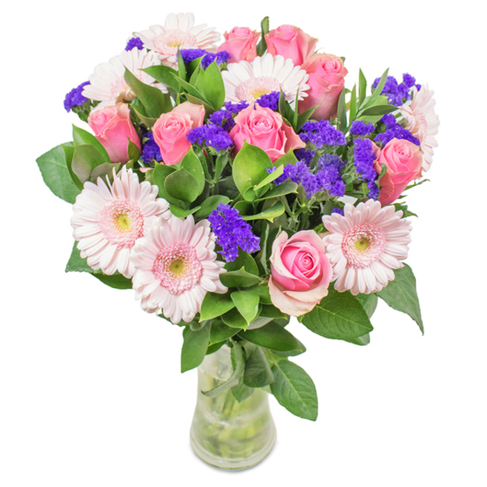A beautifully composed bouquet, nestled within a slender, transparent glass vase, stands out against a crisp white background-echoing Belvedere's fresh and inviting spirit. Around seven to nine pink roses form the structural heart of the arrangement, with petals coiled gracefully or just opening to reveal elegant spiral forms reminiscent of classic English gardens. Soft pink gerbera daisies, five to seven in number, surround the roses with broad, cheerful faces and gentle, ivory-tinged centres-much like blossoms found at local Belvedere flower stalls. Deep purple statice or limonium clusters intersperse the display, adding vivid colour and intricate texture that draw the eye and evoke wild blooms from Lesnes Abbey Woods. Robust green foliage encircles the bouquet's base, offering a rich, natural framework and enhancing the overall sense of freshness and vibrancy. The clear vase, with its visible crisscrossing stems and glint of clean water, underscores the bouquet's artisanal craftsmanship and recent harvest. This lush, expertly arranged display, available from Belvedere Flowers, is ideal for occasions such as birthdays, anniversaries, or thoughtful gifts-embodying the joy, warmth, and sense of community that define Belvedere.